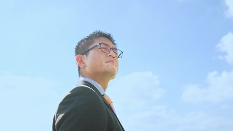 Young Asian businessman looking up at the sky.