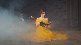 Video with noise. book without cover design. fantasy woman princess sits on floor reading. Beauty yellow long vintage dress. Enchanted prince man with horns on head. Room gothic smoke, candles burning