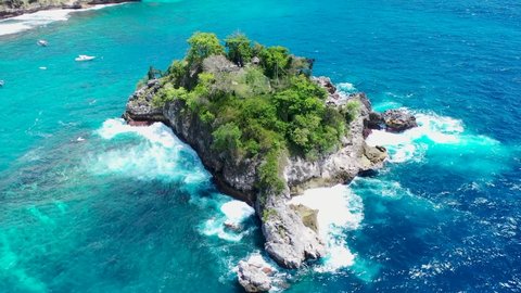 Rotation around the rock island. Cinematic aerial video of Tropical Island with turquoise water waves crushing rocky cliffs, Crystal Bay Beach, nusa penida, bali, Indonesia