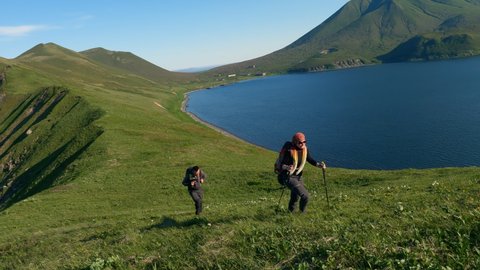 Couple tourists walking on krenitsyn volcano on the Kuril islands, watching the sunrise, hiking tourism, mountains at sunrise. Concept of nature and wildlife of Japan and kuril ridge
