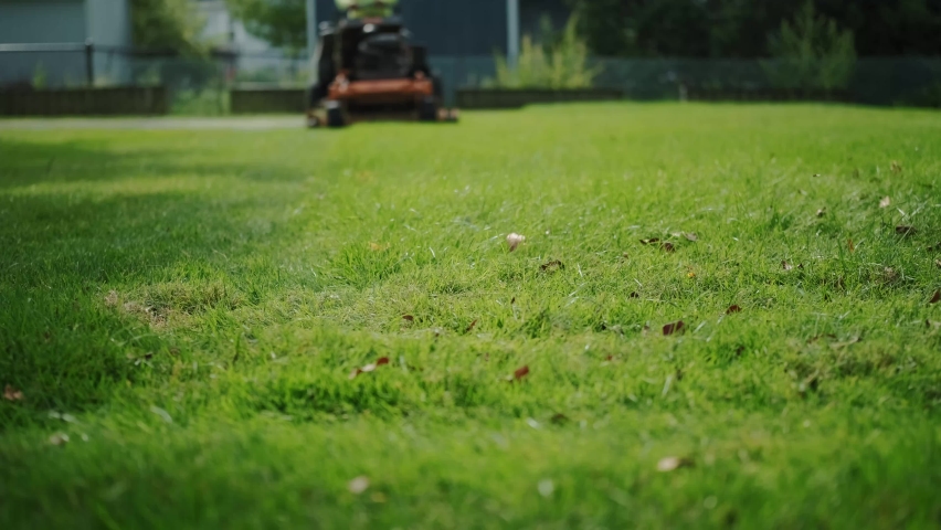 Man on lawn tractor mowing lawn on backyard. Slow motion.  Royalty-Free Stock Footage #1080625157