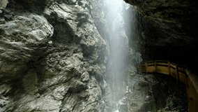 Water are falling down from the top of the mountain into the narrow, dark gorge, it looks like heavy rain. a 4K video clip, Liechtensteinklamm, Austria.