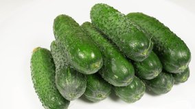 Close-up view 4k stock video footage of tasty fresh organic cucumbers laying stacked on white plate. Vegetables from farmer garden