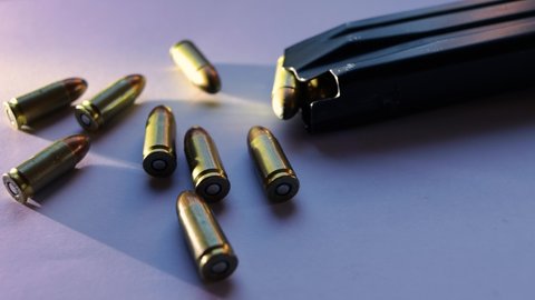 9mm caliber parabellum bullets isolated with grazing light next to a magazine of pistol ammunition