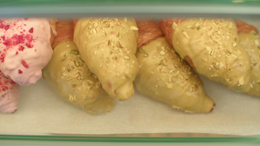 many different sweet pastries on the showcase of the cafe. many different croissants with different fillings behind the glass.