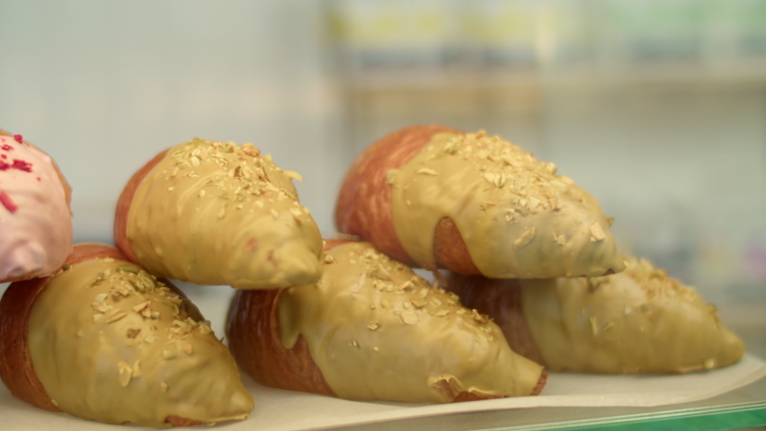 many different sweet pastries on the showcase of the cafe. many different croissants with different fillings behind the glass.