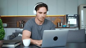 Handsome attractive man guy freelance employee , businessman, student of university in wireless headphones talking by video conference via mobile application. E- learning and remote work concepts