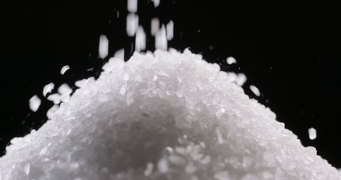 Close up shot of salt granules falling. Spice particles being dropped. Bath cosmetic salt forming a pile 4k footage