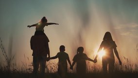 Happy family at sunset. Silhouette of group of people walk in park. Happy child with parents holding hand. Family is walk in park on grass. Happy family concept. Parents hold hand of their child. - Powered by Shutterstock - Get 15% off with code: PIKWIZARD15