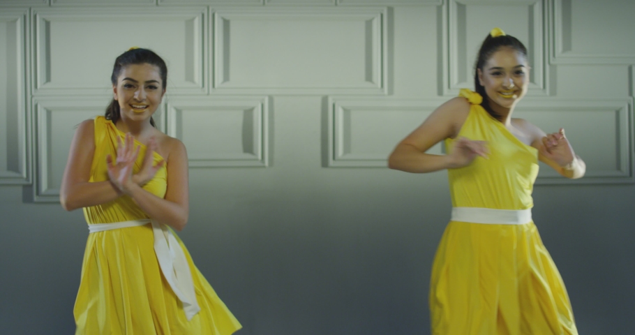 4k Group of beautiful , funny, stylish girls in yellow dresses dancing inside pavilion with grey background  . Synchronized dance of female ensemble for video clip  Woman dancers with the same outfit  Royalty-Free Stock Footage #1080648857