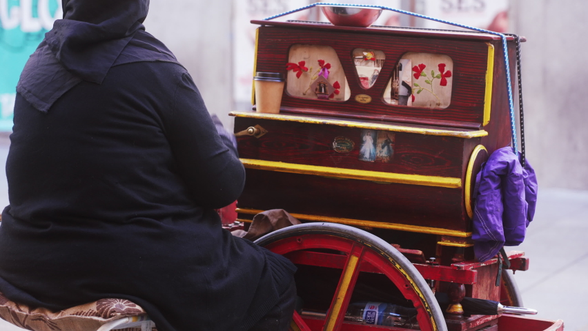handheld shot of a street performer playing a squeeze box, musician with organ grinder in the street of Madrid