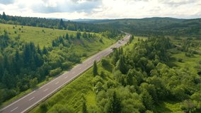 The drone follows a cyclist riding on a mountain road. Carpathian mountains, Ukraine. Cinematic aerial shot. Concept of outdoor activities. Explore the beauty of world. Filmed in 4k, drone video.