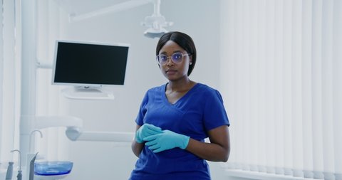 Young african american woman dentist without mask smiling looking straight at camera in modern well-equipped dental office