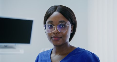 Young woman doctor of african american appearance without mask smiling looking directly at the camera in a modern bright clinic