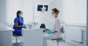 A dentist in disposable blue gloves takes a medical instrument to check a patient's tooth, close-up