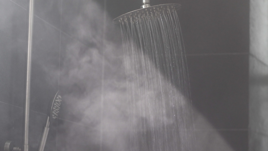 Running hot water streams make vapor in sunlight ray in grey tiled bath cabin equipped with deluxe thermostatic shower system Royalty-Free Stock Footage #1080666134