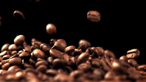 The super slow motion of the coffee beans fall into a pile. On a black background. Filmed on a high-speed camera at 1000 fps.