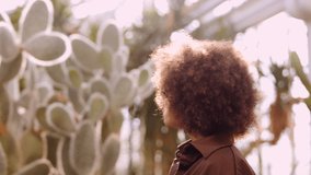 Handheld Medium Slow Motion Shot Of Young Woman Looking Around In Sunlit In Botanical Gardens