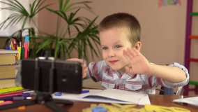 A preschool boy is talking and waving his hand to his teacher while looking at his smartphone.