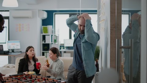 Man playing foosball game at table with woman and losing, having drinks after work. Colleagues meeting to drink beer and have fun with football game, enjoying free time after hours