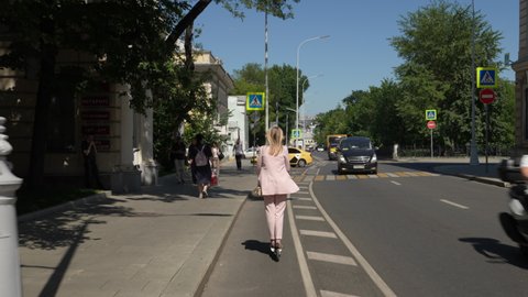 Moscow, Russia-september 2021: A young woman in a business suit rides an electric scooter along a dedicated lane in a modern metropolis. back view