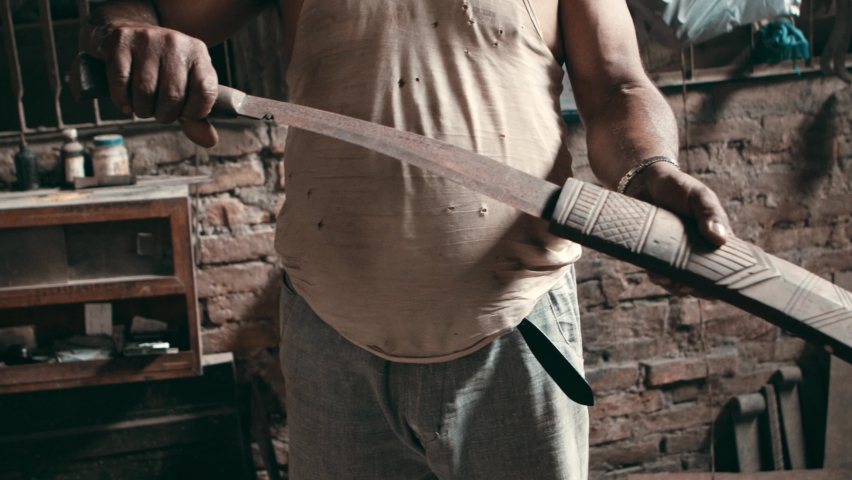 Man slides large kukri knife into a wooden sheath