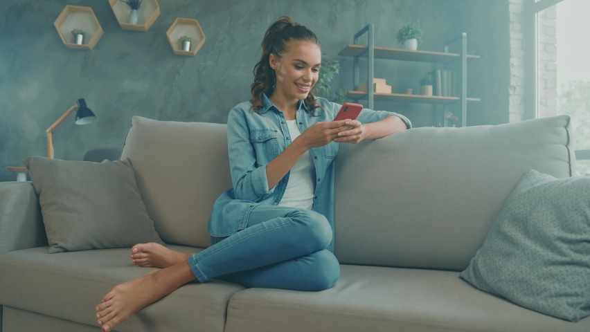 Positive nice cute lady sit cozy sofa texting friends telephone remote chat