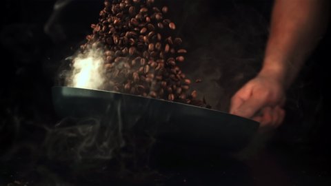 Super slow motion of coffee beans roasted in a pan with hot steam. On a black background.Filmed on a high-speed camera at 1000 fps.