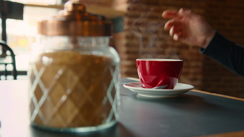 Female hand take cup of steaming coffee from table and take a sip. Young woman in cafe or restaurant drink americano or filter coffee from red mug. Cinematic breakfast footage Royalty-Free Stock Footage #1080688307
