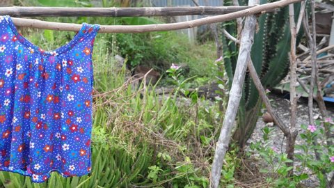 Old round-necked sleeveless blue red floral clothing on wooden clothes line  in rural natural vintage background. Concept of vintage, countryside place, retro scene, lifestyle.