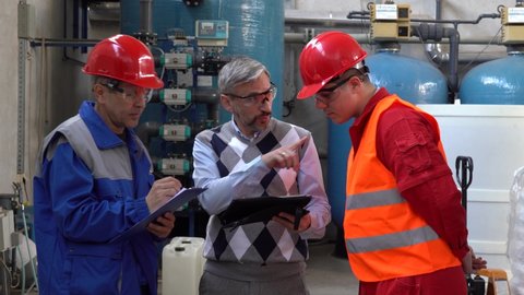Technical Manager Using Digital Tablet and Talking With Engineer and Worker in Personal Protective Equipment In A Factory Environment. Digital Technology and Teamwork Concept. Industry 4.0