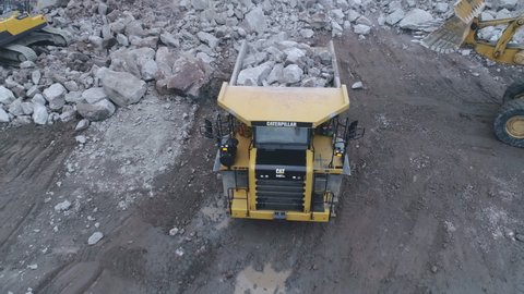 Caterpillar loader and Volvo excavator loads Caterpillar dump truck with stones in a granite quarry Russia 18.09.2020