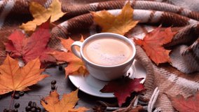Autumn, fall leaves, hot cup of coffee and warm plaid on a wooden table background. Seasonal, morning coffee, sunday relaxing and still life concept. Camera movement in a circle