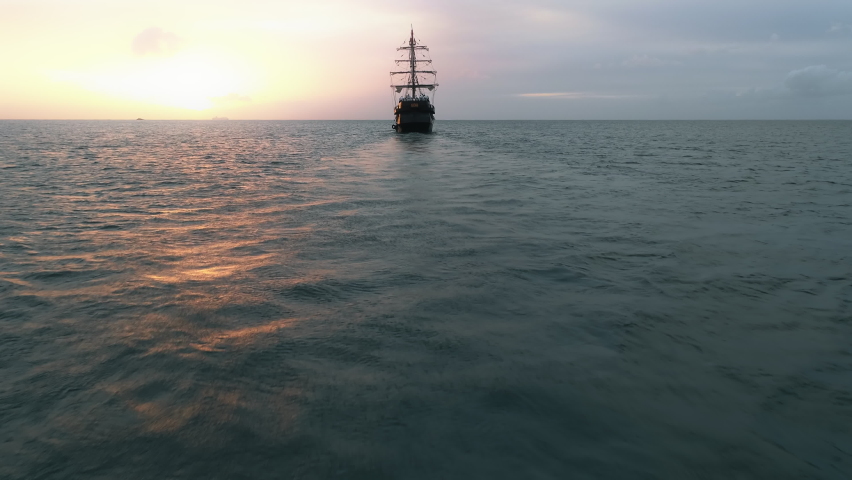 Large medieval ship sailing Caribbean sea at golden pink sunset. Cinematic old medieval ship gracefully sailing in the open sea toward horizon. Dream trip, ideal summer vacation on Saint Lucia island Royalty-Free Stock Footage #1080704810