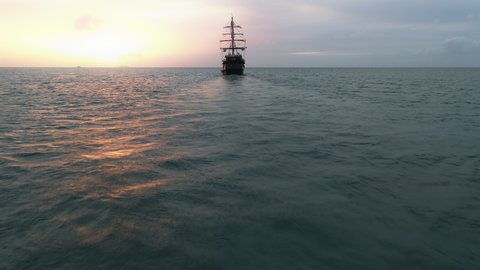 Large medieval ship sailing Caribbean sea at golden pink sunset. Cinematic old medieval ship gracefully sailing in the open sea toward horizon. Dream trip, ideal summer vacation on Saint Lucia island