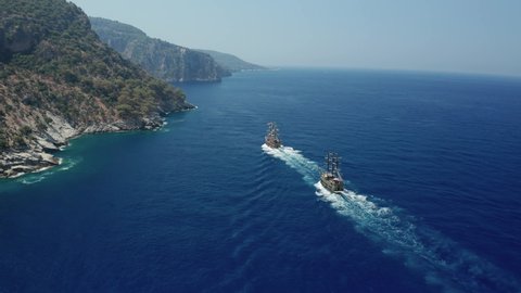 Amazing panoramic aerial 4k view from drone of tourism pirate ship going from Oludeniz to Butterfly Valley and Kabak Valley  along steep cliffs and beautiful bays on a bright and sunny day in Fetihye 