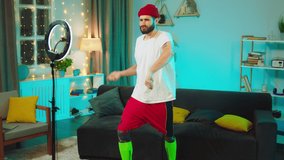 In the living room attractive dancing man influencer making funny video for his social media account recording video on smartphone