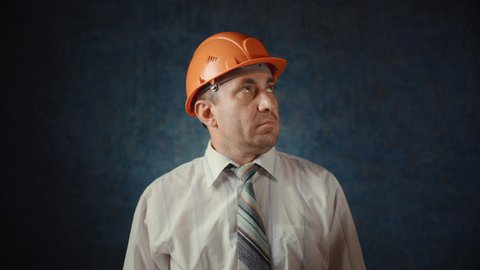 A man in a construction helmet loosens his tie around his neck.