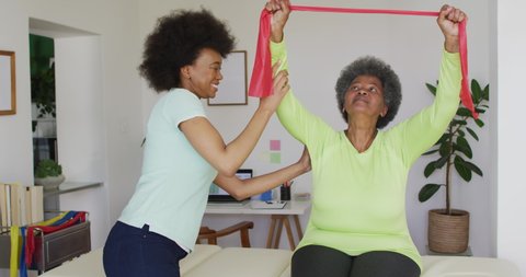 Happy african american female physiotherapist helping senior female patient exercise at home. senior healthcare and medical physiotherapy treatment.