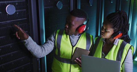 African american computer technicians using laptop working in business server room. digital information storage and communication network technology