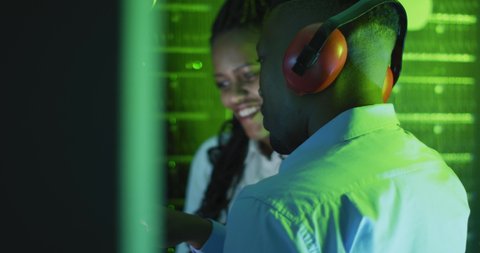 African american computer technicians wearing headphones working in business server room. digital information storage and communication network technology.