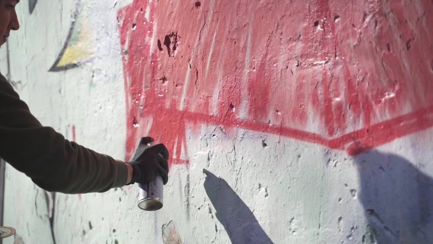 Young man painting graffiti on wall. Slow-motion