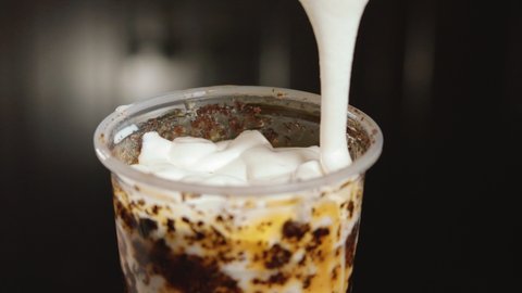 Pouring Creme Brulee Cream On Cup Of Milk Tea. - close up