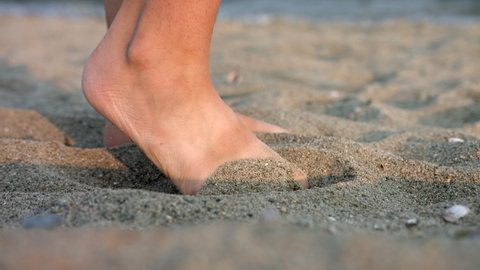 Bare Feet Of A Woman Playing Sand At The Beach. close up