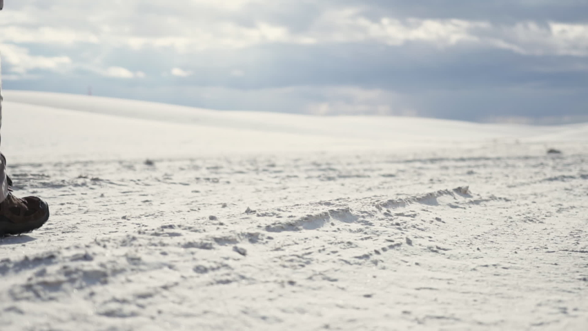 Two people walk by camera in middle of White Sands New Mexico, slow motion