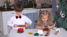 Closeup view 4k video of two cute little kids cooking sweet holiday cookies in Christmas kitchen. Brother and sister helping their mama to cook holiday dinner to Xmas party