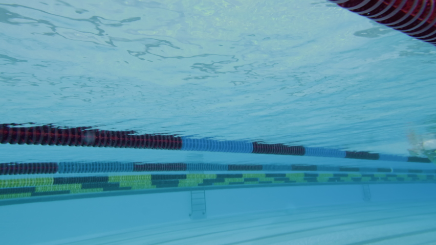 Underwater and upside-down shot of a Caucasian female swimmer in action. The swimmer performing the freestyle swim technique with an open turn. Royalty-Free Stock Footage #1080729494