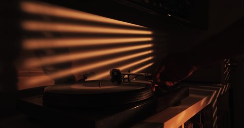 Shot of a hand putting a needle on a record with sun rays.