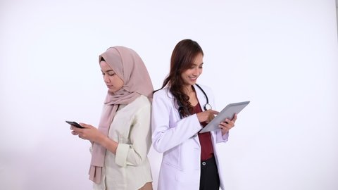 woman making a call with phone and doctor using tablet with back to back pose