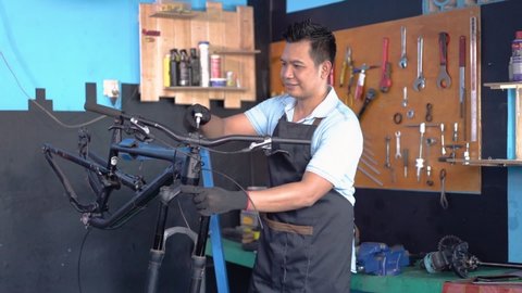 repairman in an apron getting a call via cellphone while repairing a bicycle